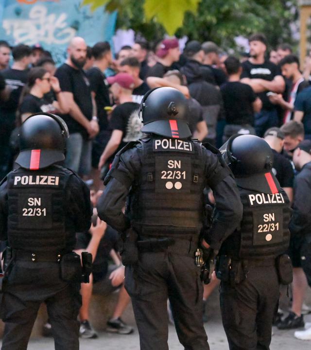 Sachsen, Leipzig: Einsatzkräfte der Polizei bewachen eine Gruppe Fußballfans in der Innenstadt. Vor dem Conference-League-Finale war es in der Innenstadt zu Ausschreitungen zwischen englischen und spanischen Fußballfans gekommen