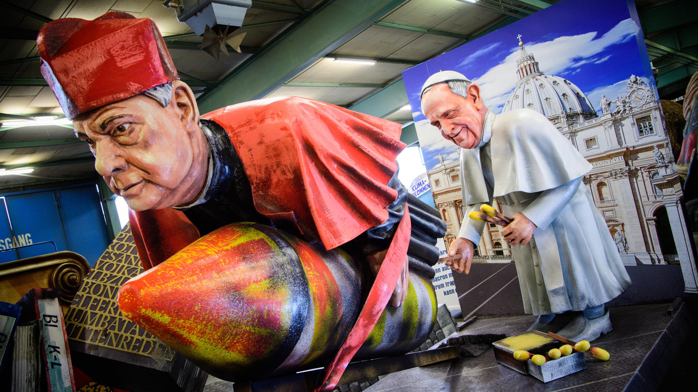 Der in Mainz geborene Kurienkardinal Gerhard Ludwig Müller wird von Papst Franziskus an einer Rakete festgebunden.