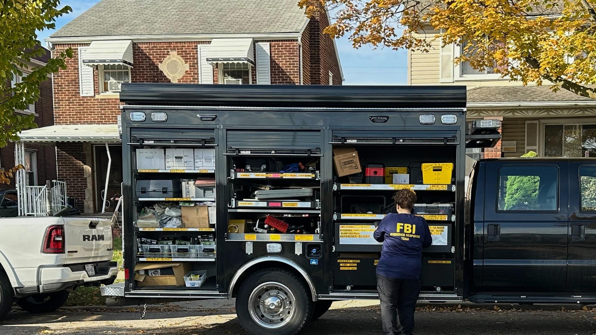 Ein FBI-Agent steht am Freitag, dem 31. Oktober 2025, neben einem Fahrzeug des Evidence Response Teams vor einem Haus in einem Wohngebiet in Dearborn, Michigan.