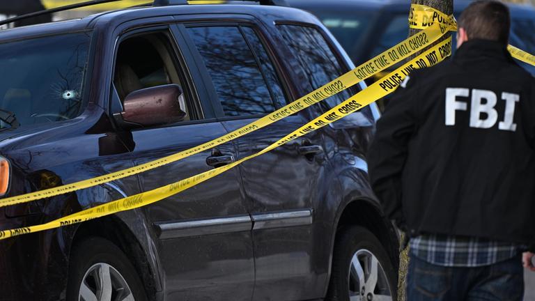 Ein Einschussloch in der Windschutzscheibe eines Autos ist zu sehen, als Beamte des FBI einen Tatort nach einem Einsatz untersuchen, an dem Bundespolizisten beteiligt waren.