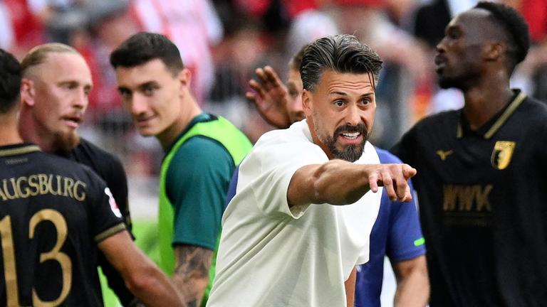 Augsburgs Trainer Sandro Wagner (M.) jubelt, während seine Spieler das dritte Tor im Bundesligaspiel gegen den SC Freiburg am 23. August 2025 in Freiburg feiern.