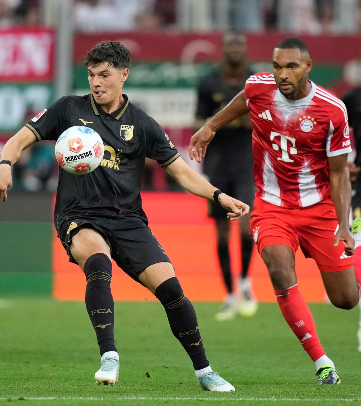 Die Spieler von FC Augsburg und FC Bayern München kämpfen.