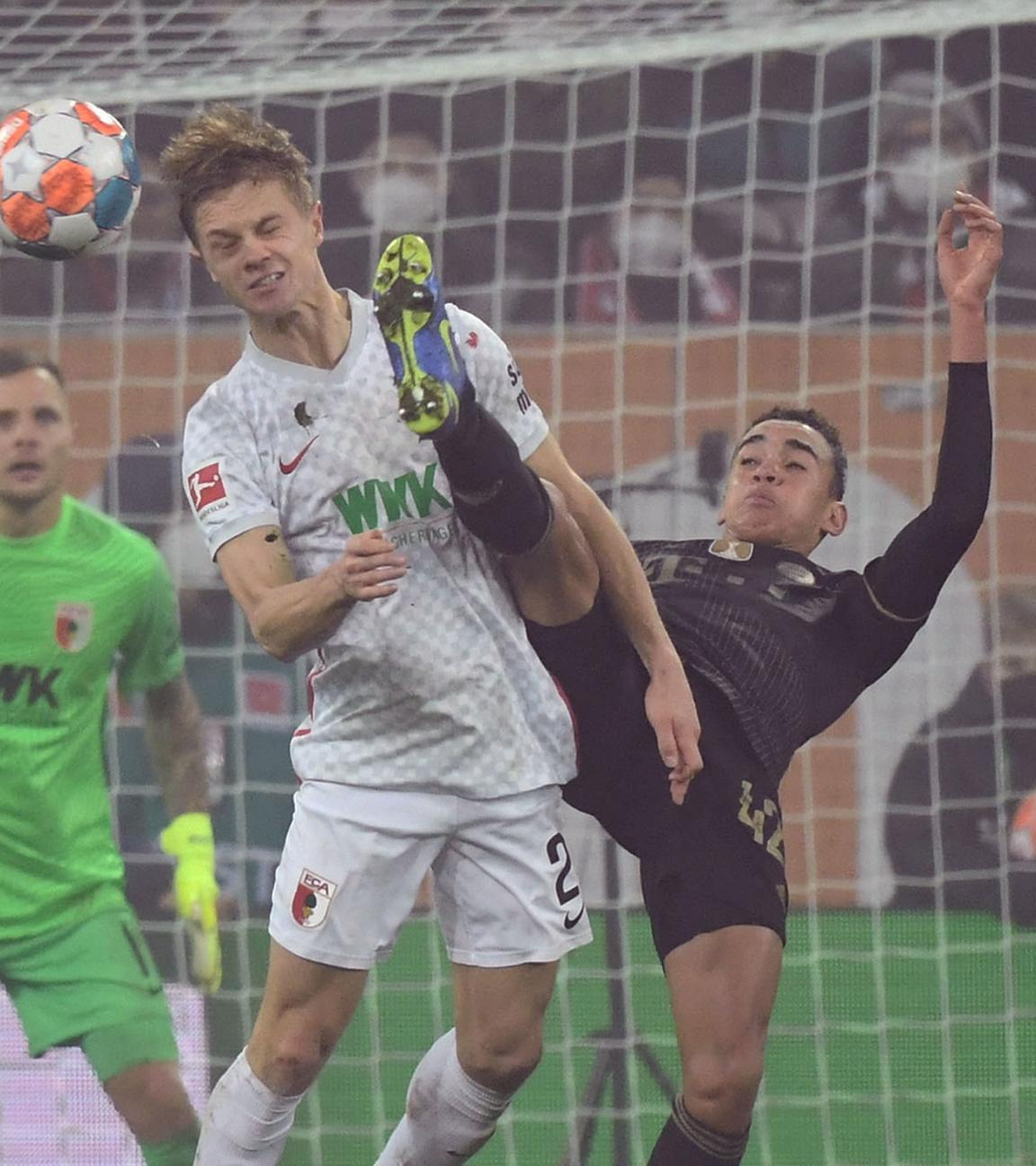 Münchens Jamal Musiala (C-R) im Einsatz gegen Augsburgs Robert Gumny während des deutschen Bundesliga-Fußballspiels zwischen dem FC Augsburg und dem FC Bayern in Augsburg, Deutschland, 19.