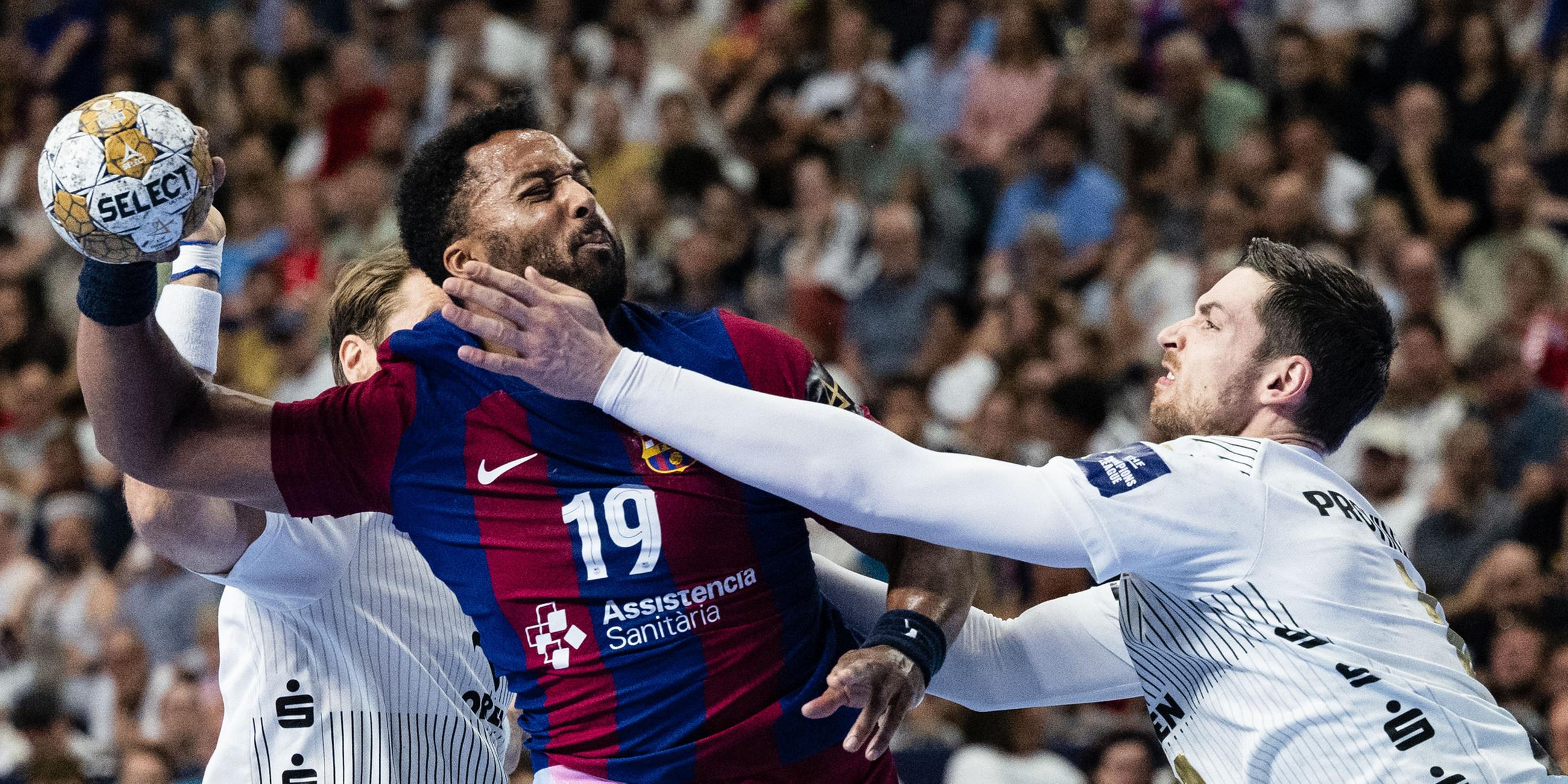 Kiels Harald Reinkind (r) versucht Barcelonas Timothey N'Guessan (M) am Wurf zu hindern.