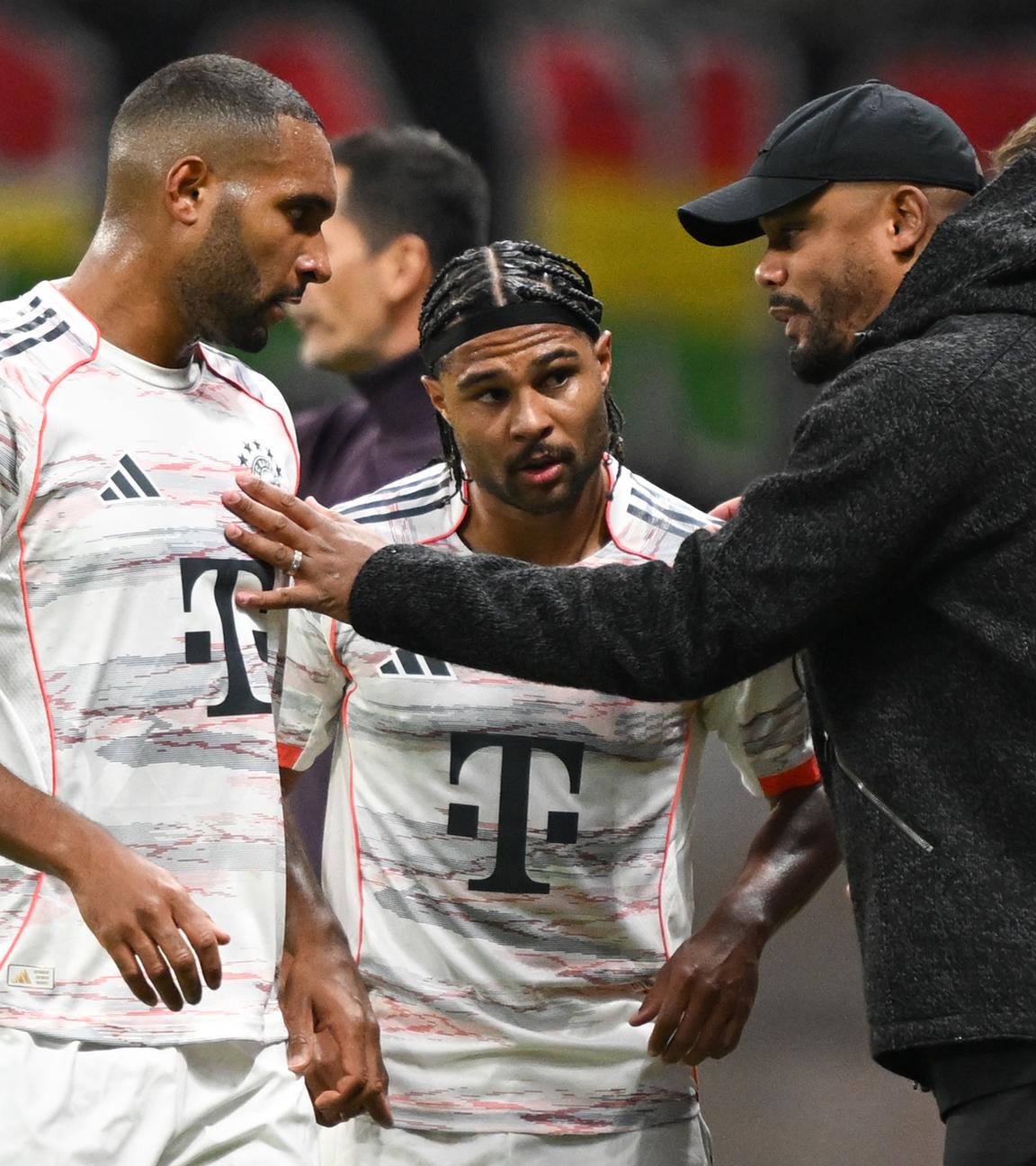 Bayern Münchens Trainer Vincent Kompany spricht an der Seitenlinie mit Jonathan Tah und Serge Gnabry.