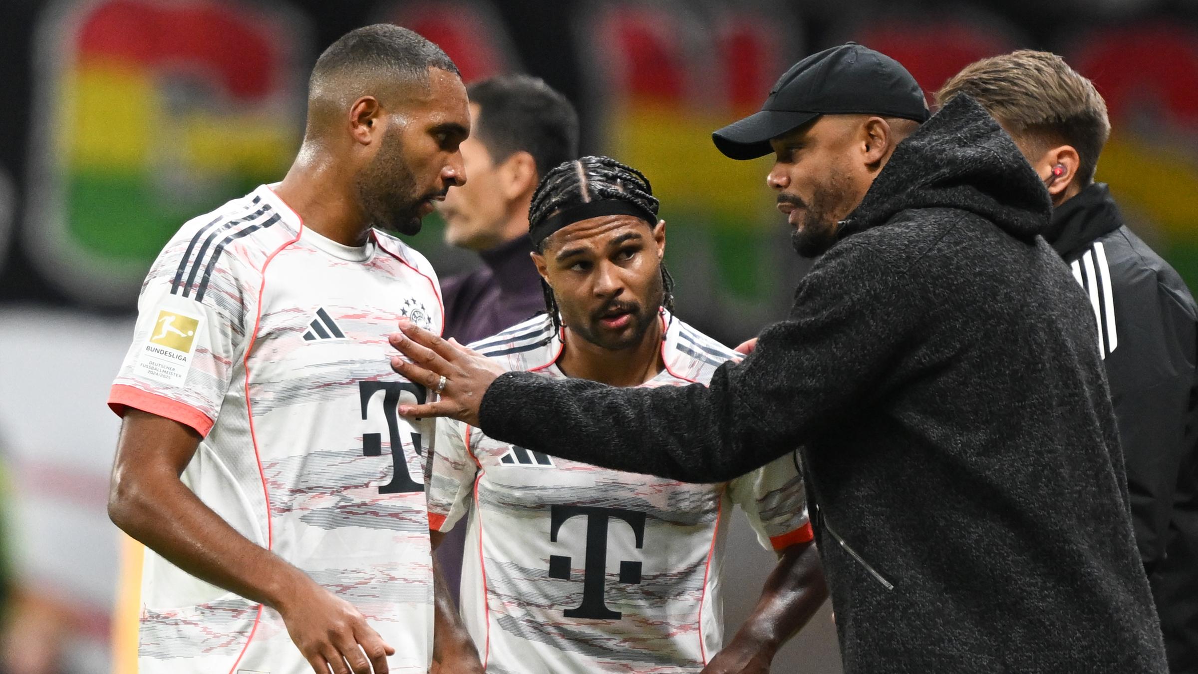 Bayern Münchens Trainer Vincent Kompany spricht an der Seitenlinie mit Jonathan Tah und Serge Gnabry.