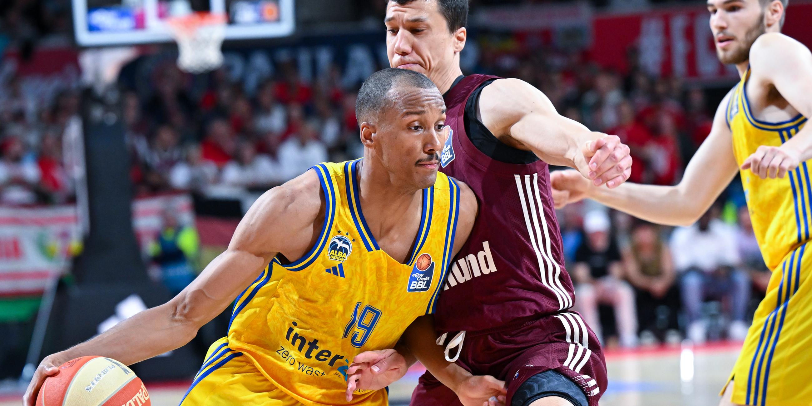 Vladimir Lucic (M) von München und Louis Olinde (l) von Berlin kämpfen um den Ball.