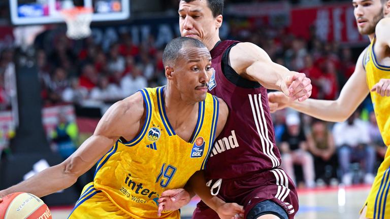 Vladimir Lucic (M) von München und Louis Olinde (l) von Berlin kämpfen um den Ball.