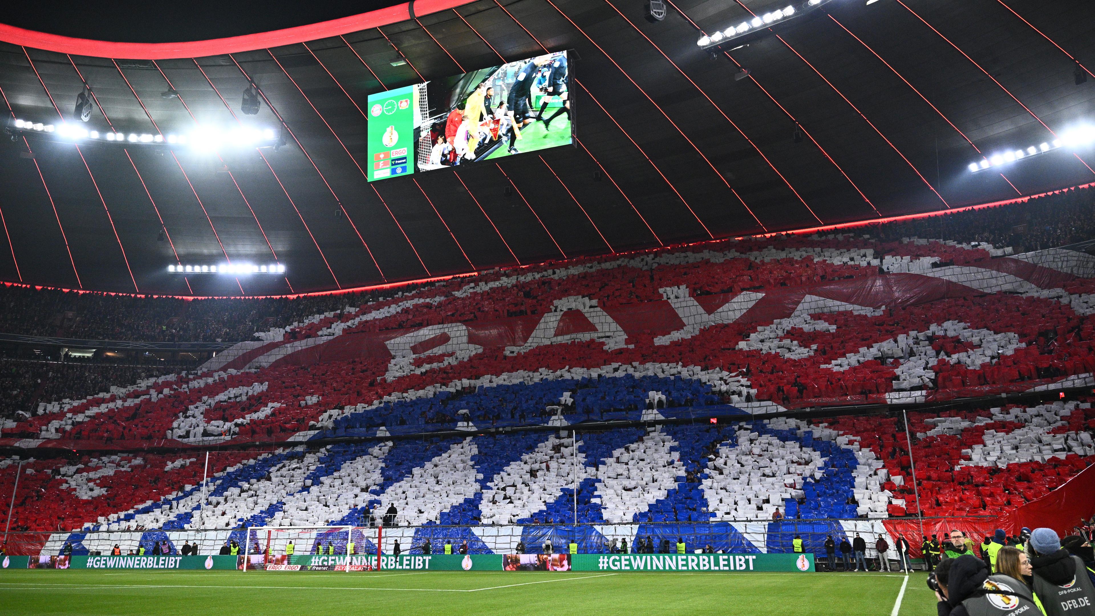 Die Fans des FC Bayern präsentieren das Vereinswappen als Choreografie während die Teams auf den Platz kommen.