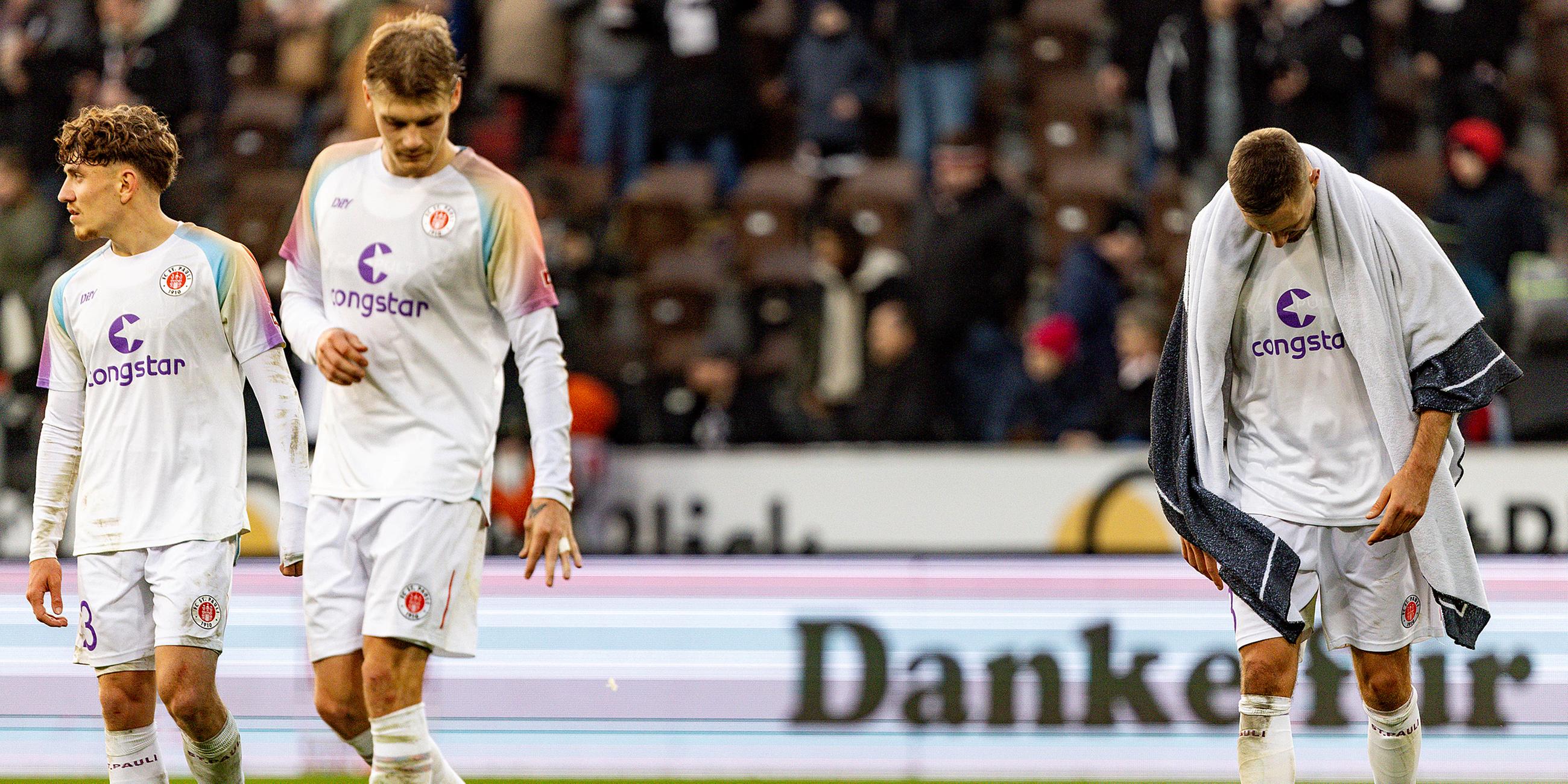 St. Paulis Philipp Treu (l-r), St. Paulis Eric Smith und St. Paulis Karol Mets reagieren nach dem Abpfiff. 