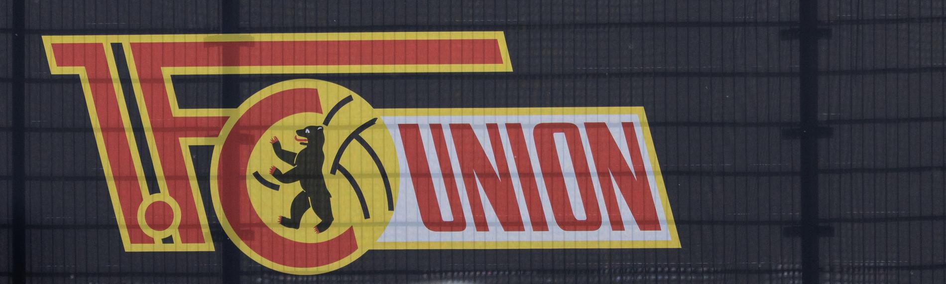 Ein Fußball liegt auf dem Rasen. Im Hintergrund ist das Logo vom 1. FC Eisern Union zu sehen.