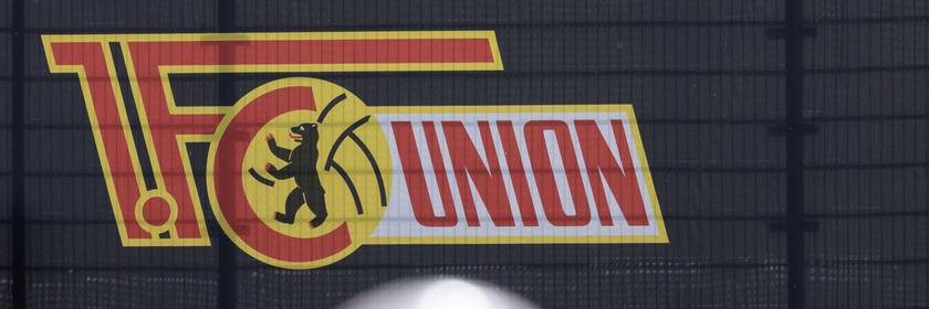 Ein Fußball liegt auf dem Rasen. Im Hintergrund ist das Logo vom 1. FC Eisern Union zu sehen.