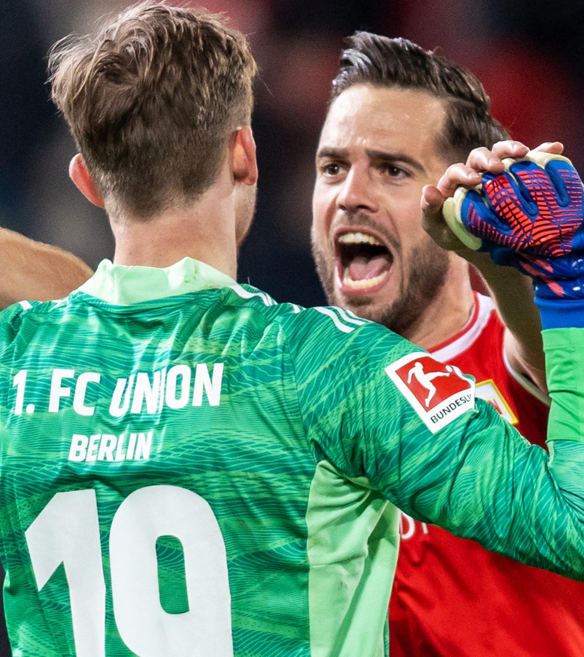 01.04.2022, Berlin: Fußball: Bundesliga, 1. FC Union Berlin - 1. FC Köln, 28. Spieltag, An der Alten Försterei. Berlins Torwart Frederik Rönnow (l) und Niko Gießelmann klatschen sich nach dem Sieg ab.