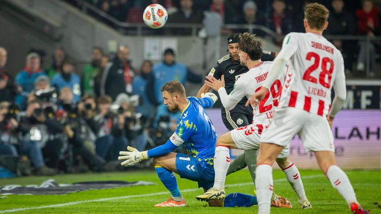 Serge Gnabry (FC Bayern) erzielt den Ausgleich zum 1:1 gegen Marvin Schwäbe (1. FC Köln), während Jan Thielmann (1. FC Köln) beteiligt ist. 1. FC Köln – Bayern München.