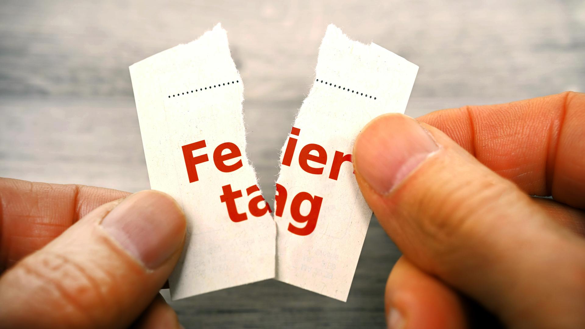 Hände zerreißen Kalenderblatt mit Aufschrift Feiertag