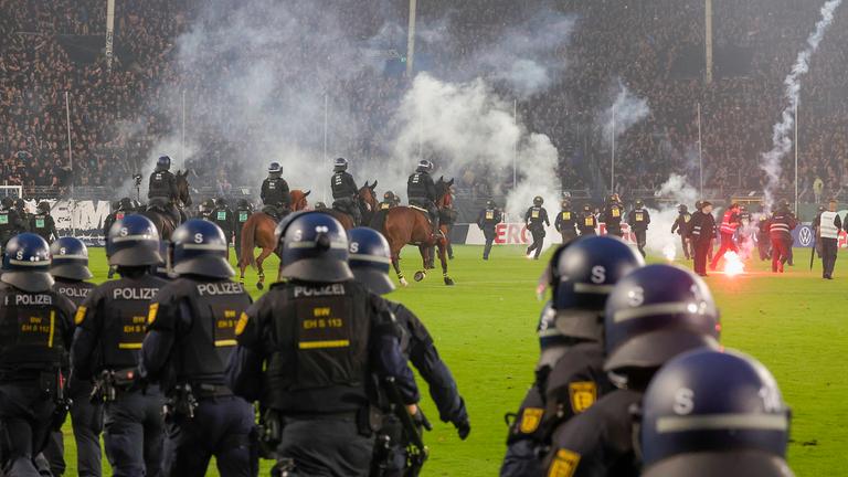 Während der DFB-Pokalpartie zwischen Waldhof Mannheim und dem 1. FC Kaiserslautern muss die Polizei das Feld stürmen
