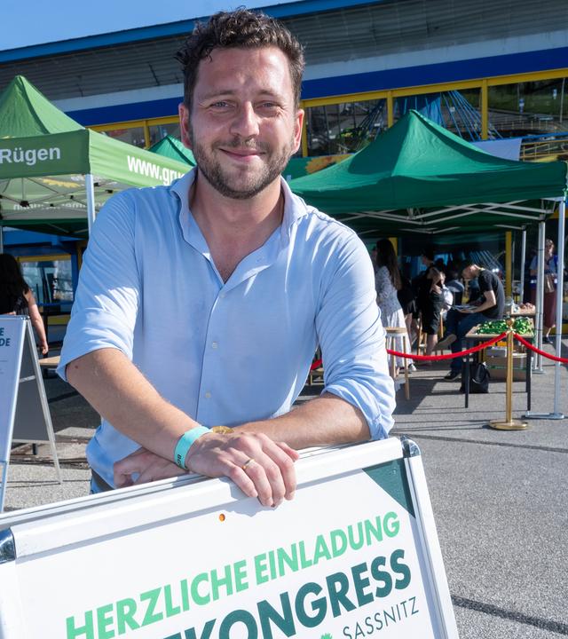 Grünen-Chef Felix Banaszak mit einem Schild, das den Ostkongress der Grünen in Sassnitz ankündigt