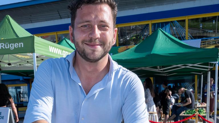 Grünen-Chef Felix Banaszak mit einem Schild, das den Ostkongress der Grünen in Sassnitz ankündigt