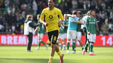 Felix Nmecha läuft im BVB Trikot über den Platz in einem Stadion.