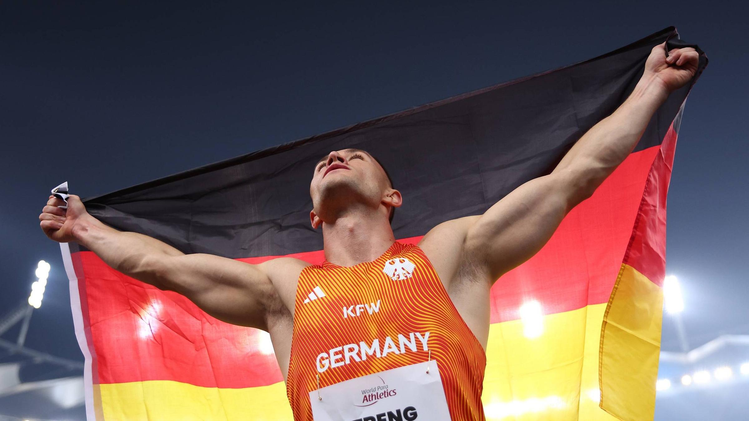Felix Streng vom Team Deutschland gewinnt am 30.09.2025 bei der Para-Leichtathletik-WM in Neu-Delhi Gold im 100-Meter-Finale (T64) und jubelt mit der deutschen Flagge.