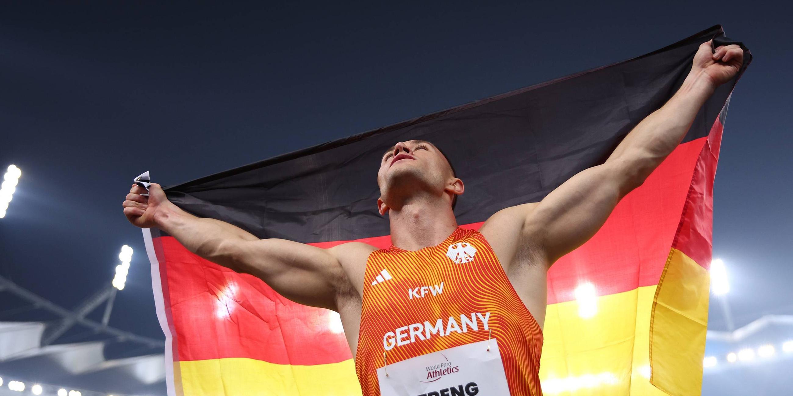Felix Streng vom Team Deutschland gewinnt am 30.09.2025 bei der Para-Leichtathletik-WM in Neu-Delhi Gold im 100-Meter-Finale (T64) und jubelt mit der deutschen Flagge.