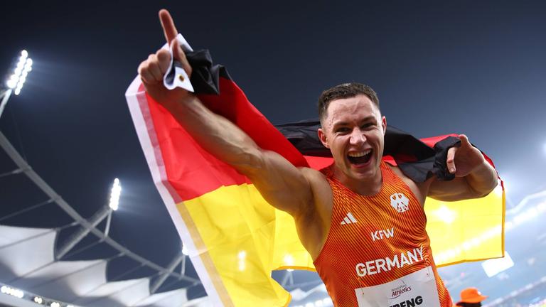 Felix Streng von Team Deutschland jubelt mit der Deutschland-Fahne auf dem Rücken über Gold im 100-Meter-Finale der Klasse T64