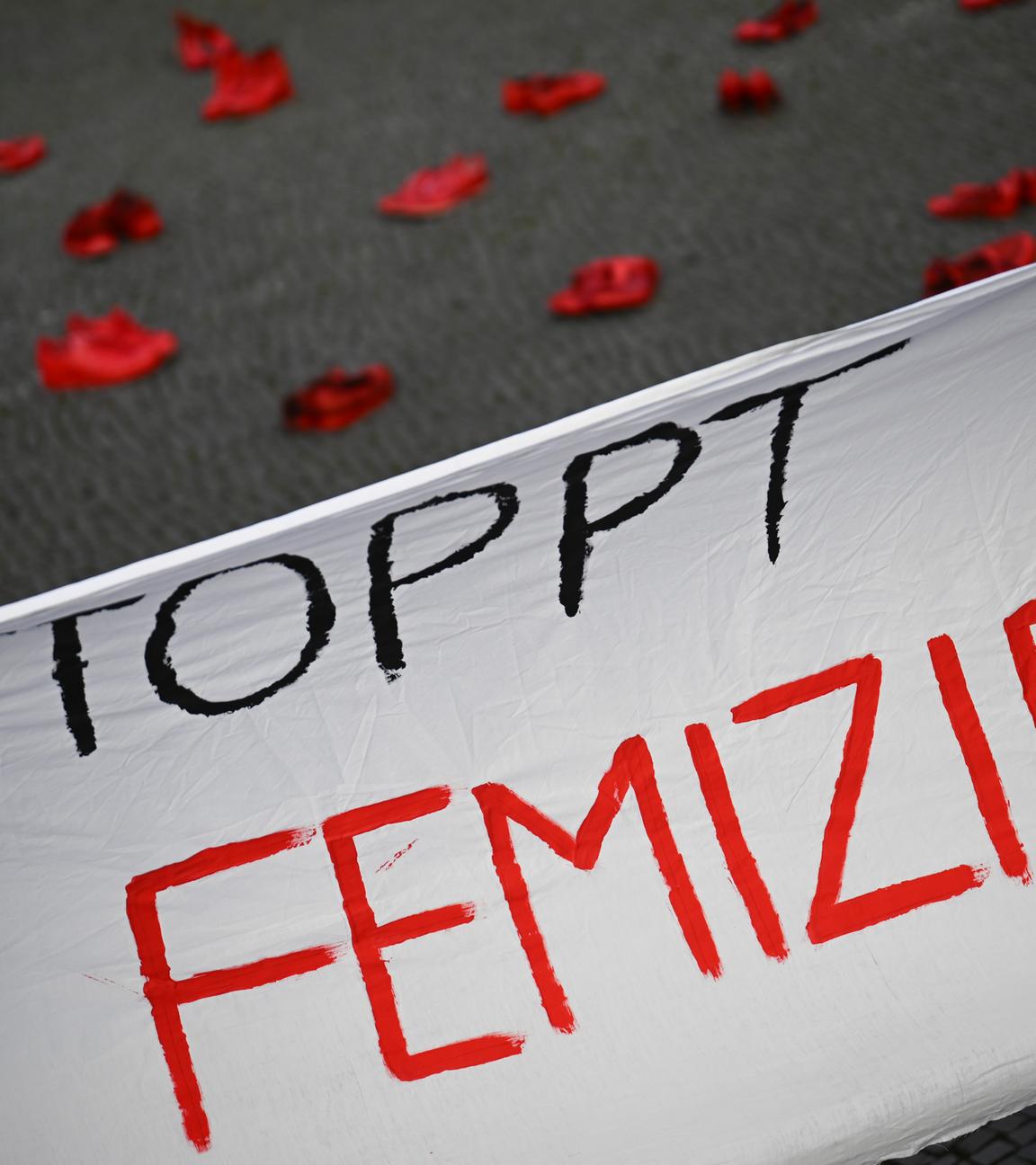 Ein Banner mit der Aufschrift «Stoppt Femizide» hängt vor roten Schuhen.
