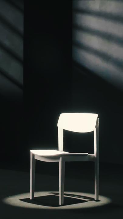 Weißer leerer Stuhl in dunkler Studio-Umgebung