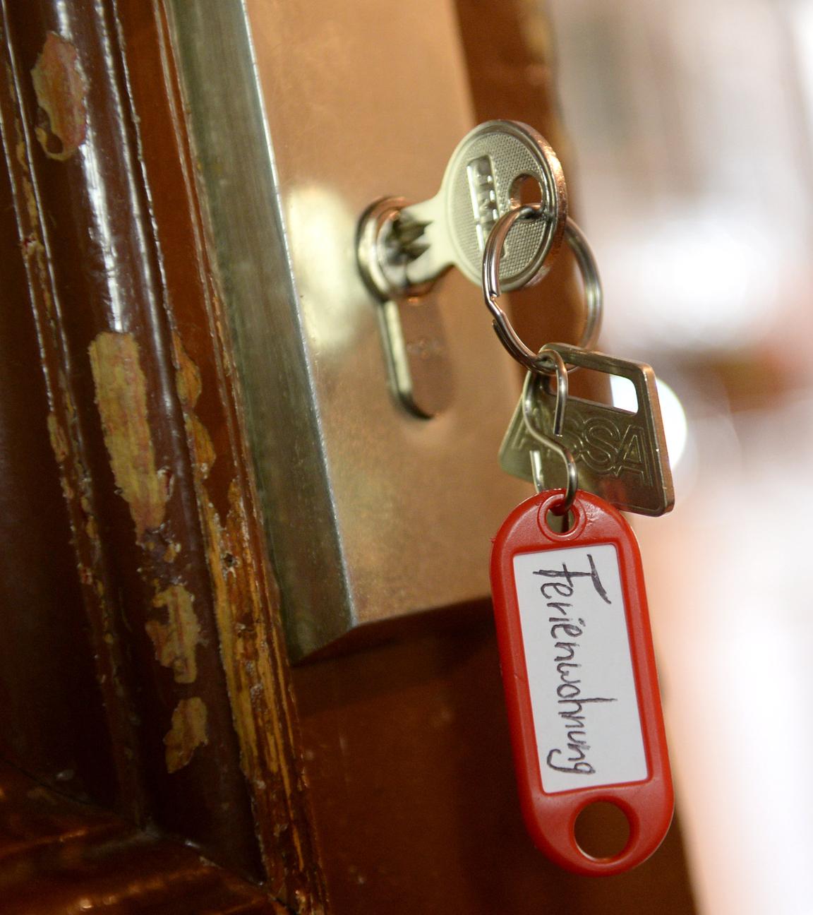 Ein Schlüssel mit einem Anhänger mit der Aufschrift "Ferienwohnung" hängt in einer Wohnungstür