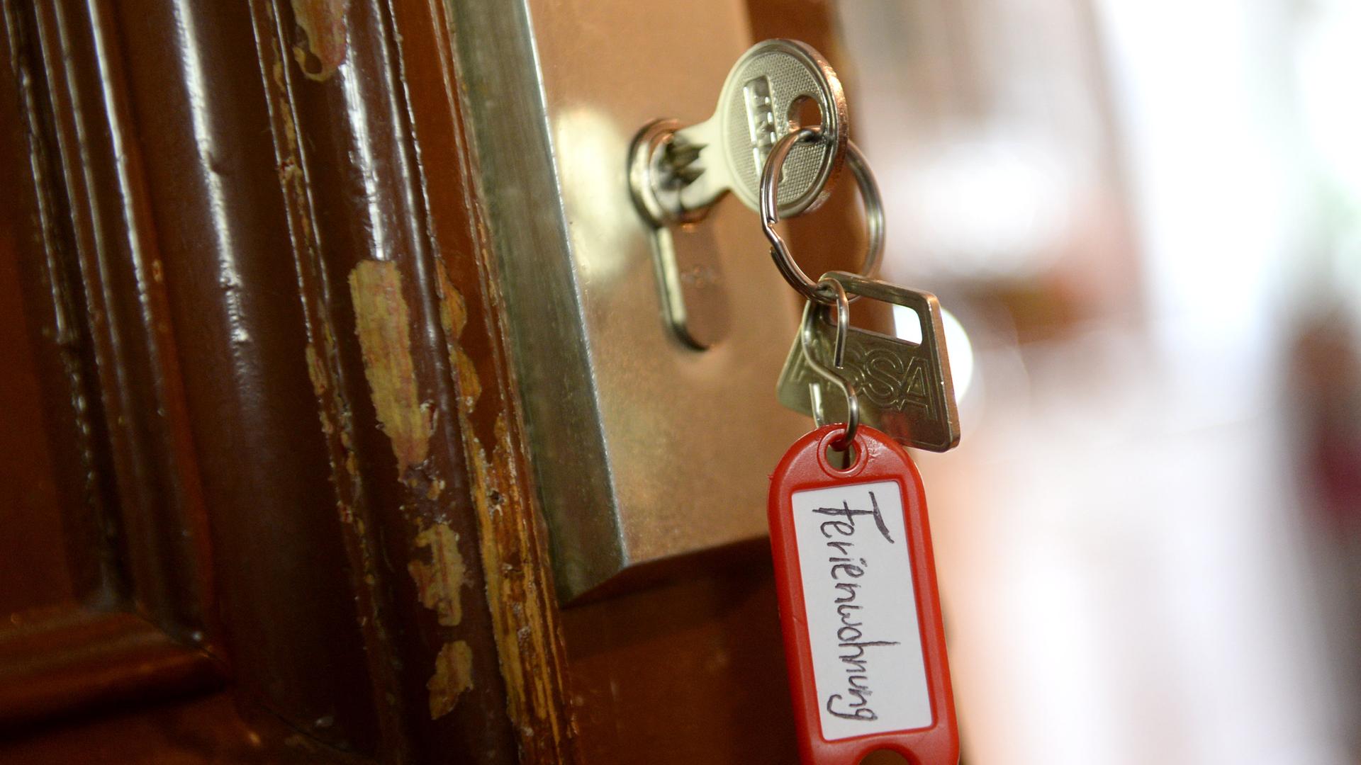 Ein Schlüssel mit einem Anhänger mit der Aufschrift "Ferienwohnung" hängt in einer Wohnungstür