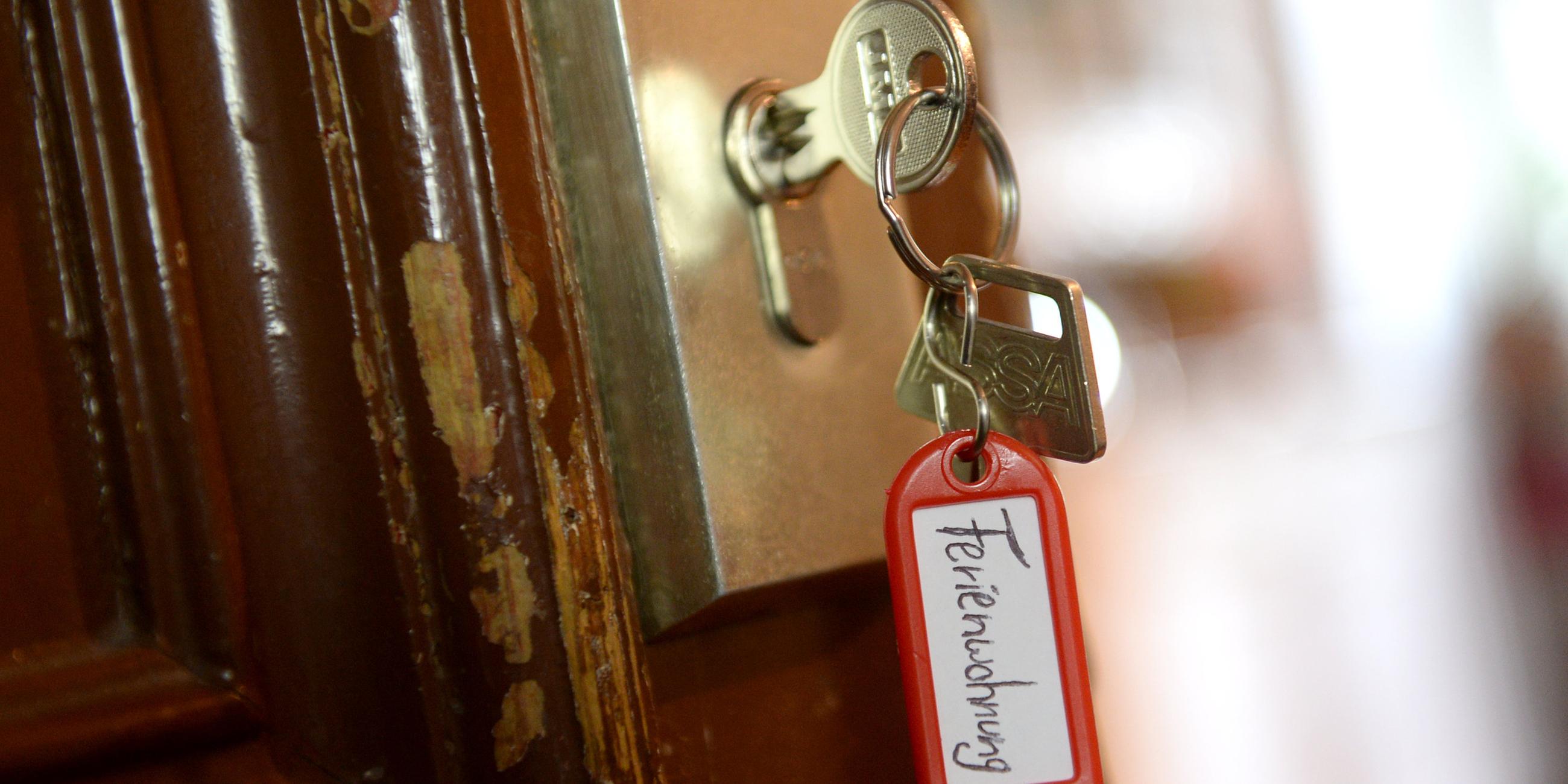 Ein Schlüssel mit einem Anhänger mit der Aufschrift "Ferienwohnung" hängt in einer Wohnungstür