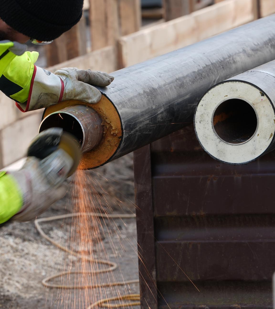 Symbolbild für Fernwärme: Arbeiter bereiten Rohre für Fernwärmeleitungen auf einer Baustelle vor