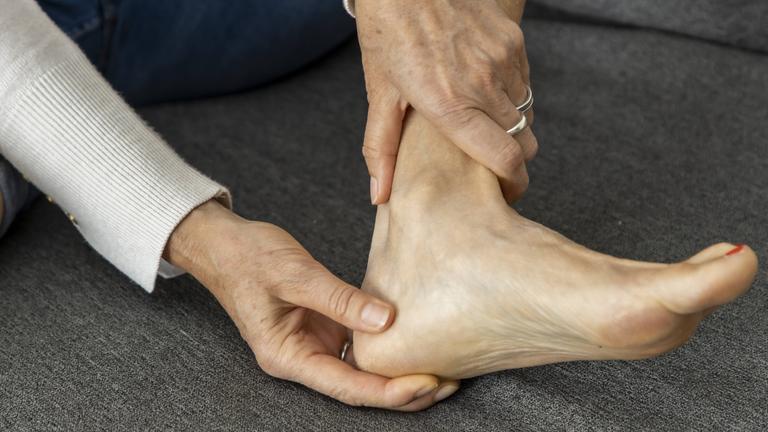 Frau hält sich den schmerzenden Fuß.