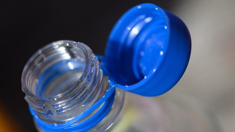 Eine Wasserflasche mit geöffneten Verschluss steht auf einem Tisch