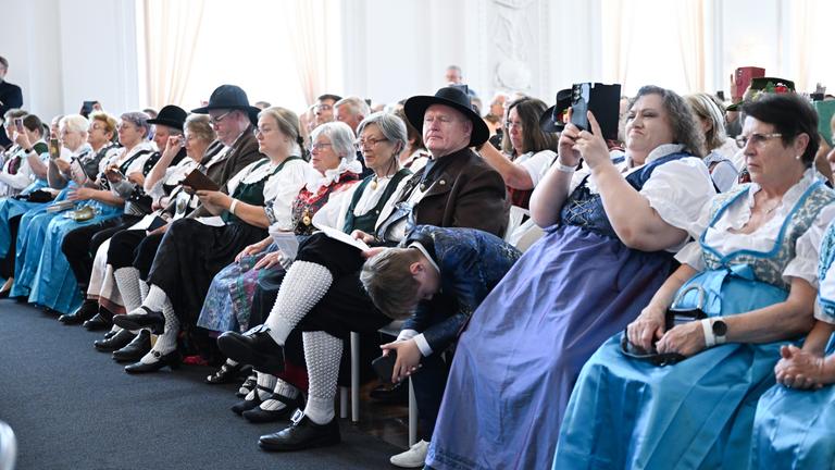 05.08.2025, Baden-Württemberg, Stuttgart: Mitglieder vom Bund der Vertriebenen sitzen in Tracht beim Festakt 75 Jahre Charta der deutschen Heimatvertriebenen im Neuen Schloss.