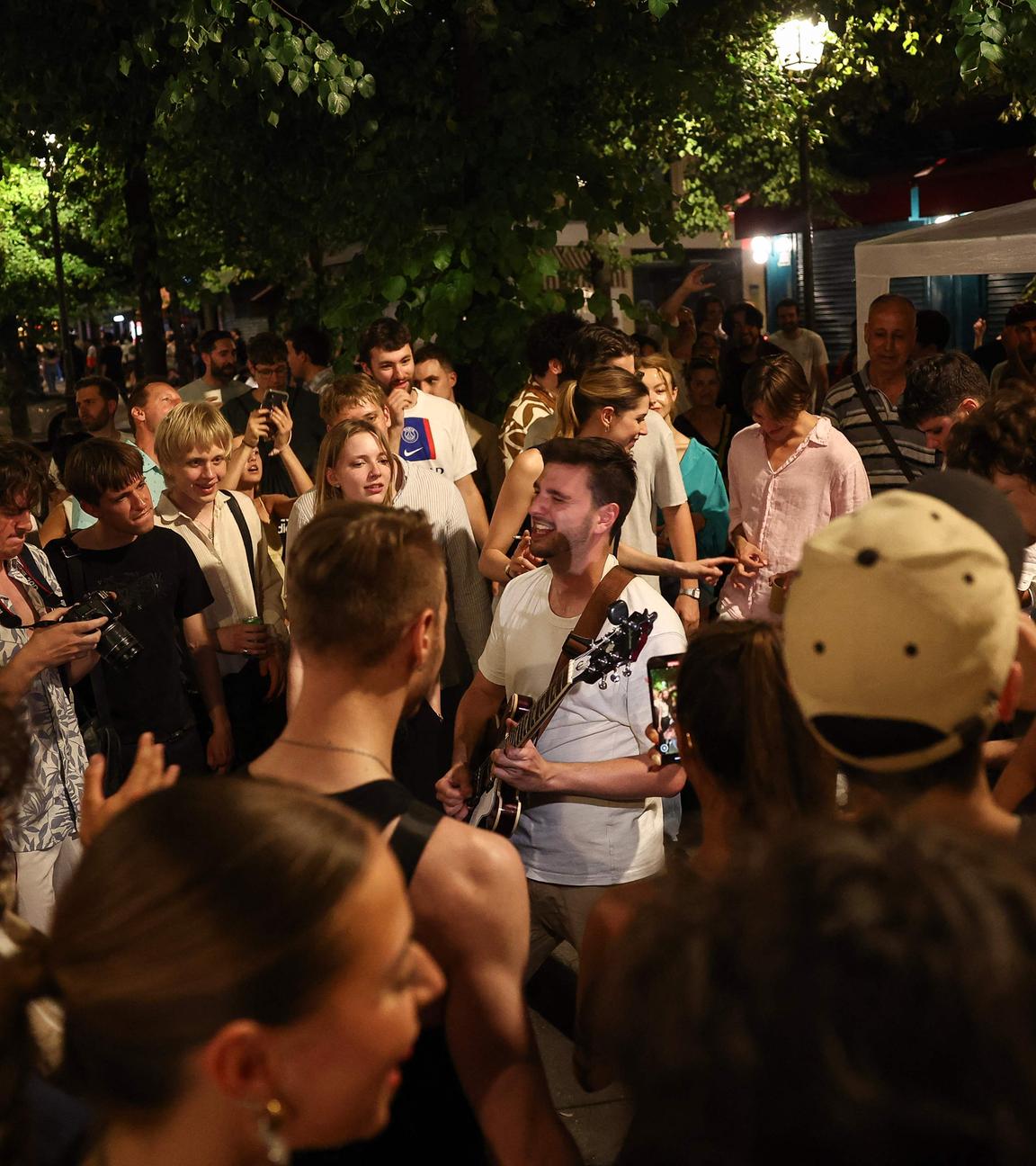 Musikbegeisterte hören einem Mann zu, der beim jährlichen französischen Straßenmusikfestival „Fête de la Musique“ Gitarre spielt.