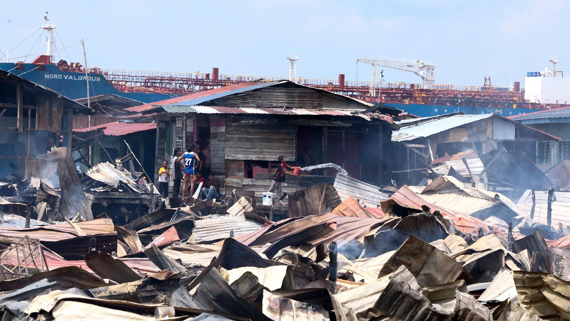 Trümmer liegen nach einem Brand in einem Küstendorf in Sabah, Malaysia, am 19.04.2026.