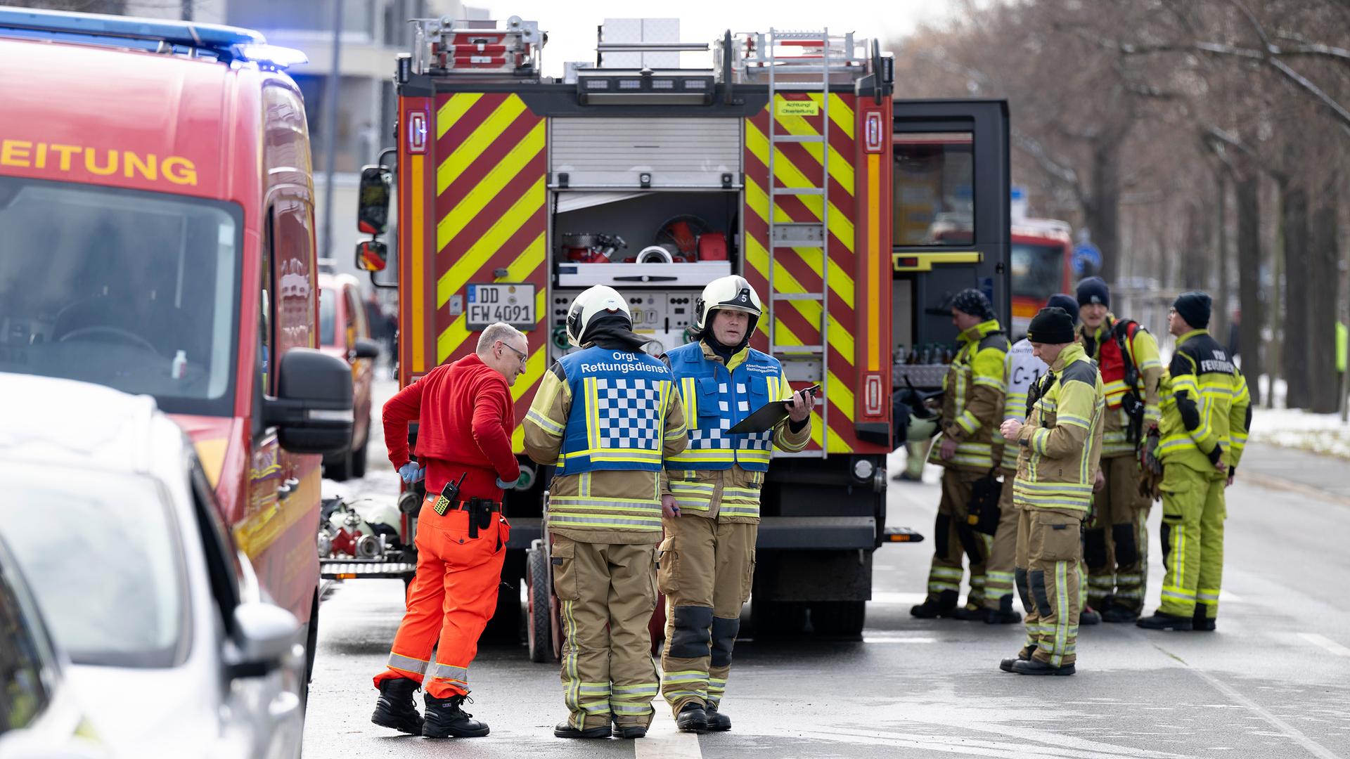 Einsatzkräfte der Feuerwehr stehen nach einem Brand in der elften Etage eines Dresdner Hochhauses am Einsatzort, aufgenommen am 15.02.2025