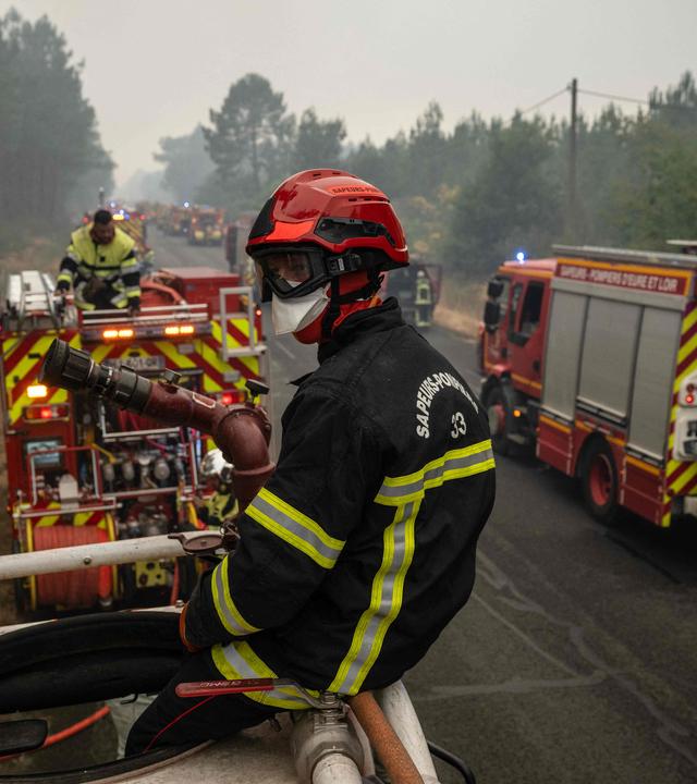 Feuerwehrfahrzeuge und Einsatzkräfte stehen nahe der südwestfranzösischen Gemeinde Lège-Cap-Ferret im Einsatz, während Waldbrände in der Region weiter wüten.