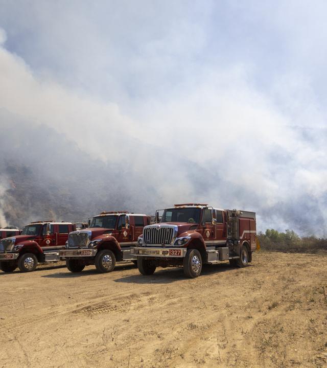 Feuerwehrautos stehen nahe des Sandy Fire in Simi Valley in Kalifornien bereit, während Einsatzkräfte gegen den Waldbrand kämpfen.