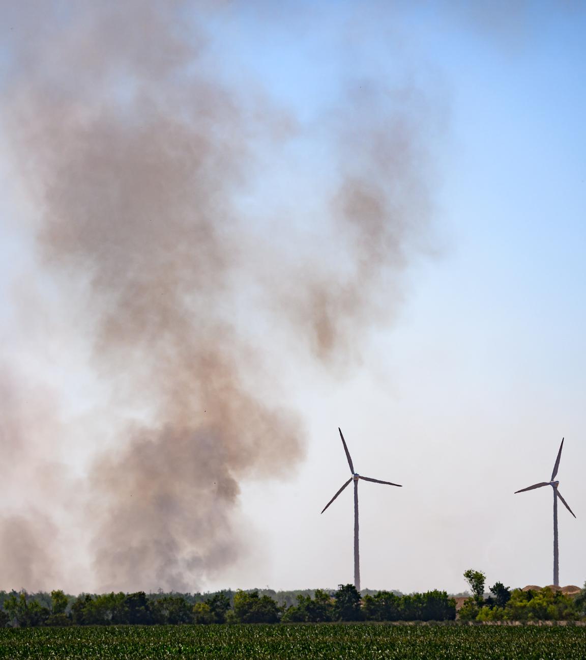 Ein Feld mit Windrädern und einer Rauchwolke