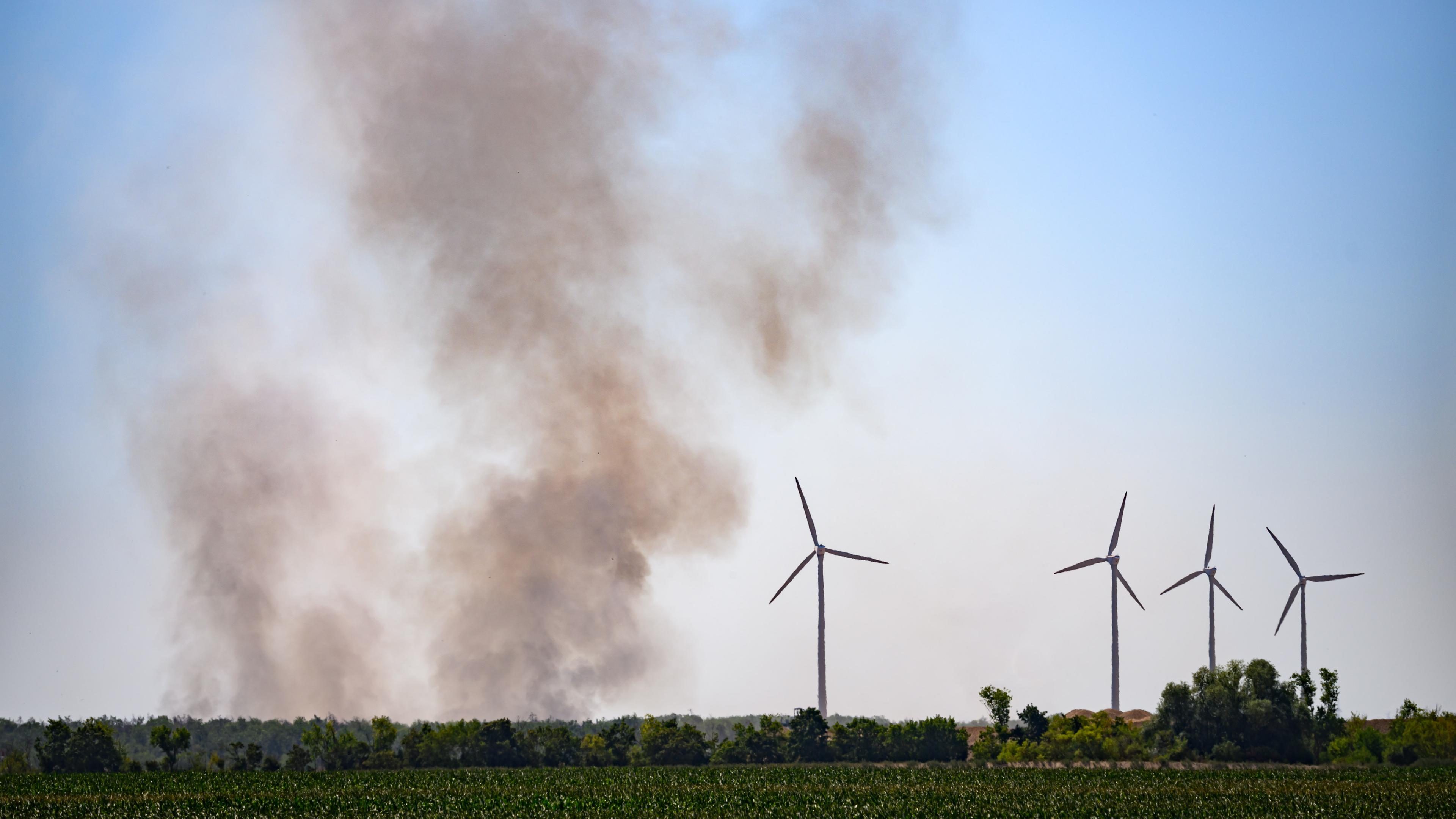 Ein Feld mit Windrädern und einer Rauchwolke