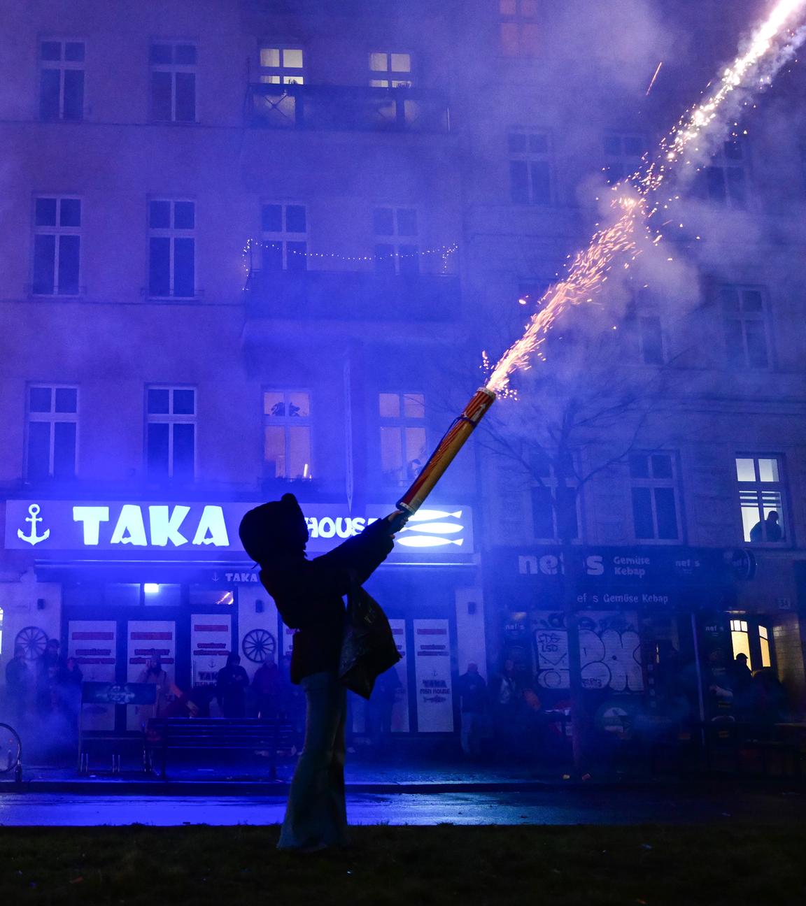 Zwei Menschen zünden während der Silvesternacht Feuerwerk aus der Hand in Berlin.