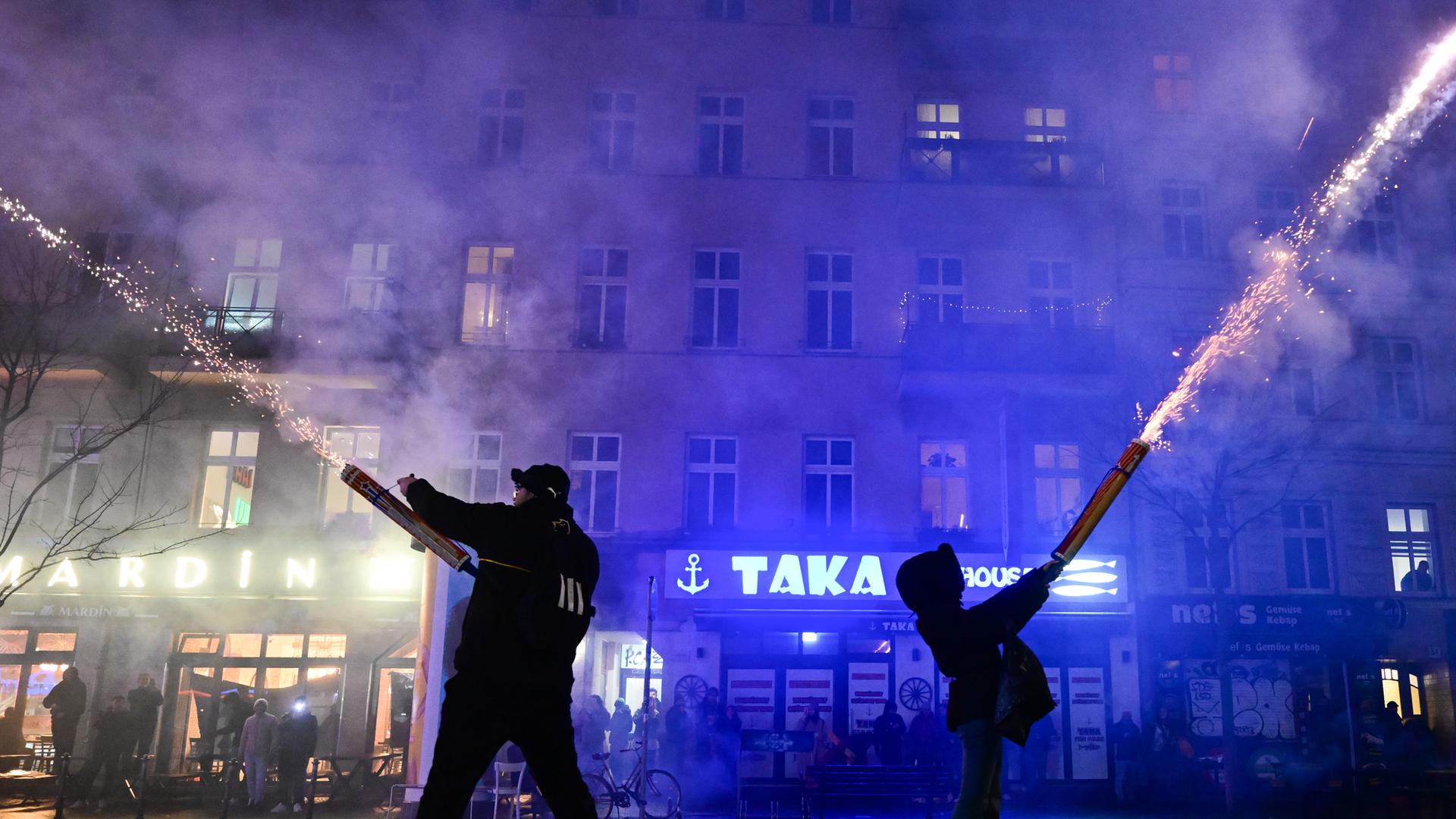 Zwei Menschen zünden während der Silvesternacht Feuerwerk aus der Hand in Berlin.