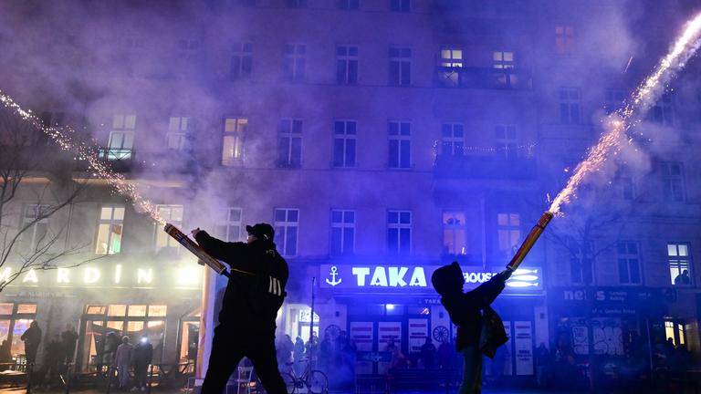 Zwei Menschen zünden während der Silvesternacht Feuerwerk aus der Hand in Berlin.