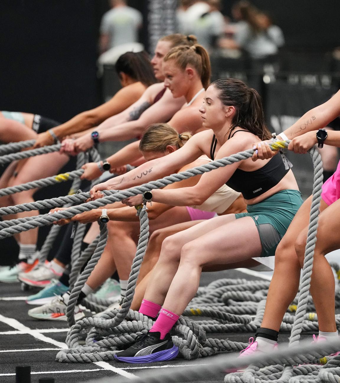 Frauen nehmen an einem HYROX-Fitnesswettbewerb auf der Gesundheits- und Fitnessmesse FIBO in Köln teil. Sie ziehen an Tauen.