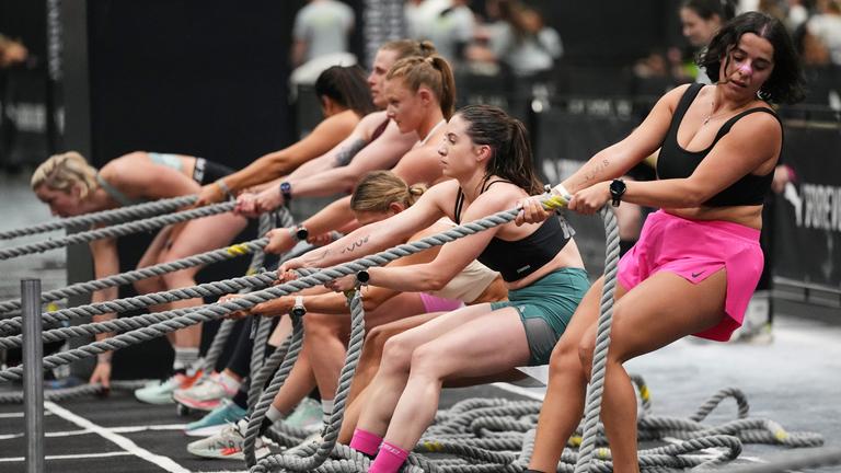 Frauen nehmen an einem HYROX-Fitnesswettbewerb auf der Gesundheits- und Fitnessmesse FIBO in Köln teil. Sie ziehen an Tauen.