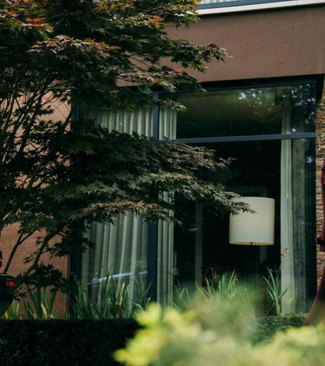 Eine Frau, die ein Businesskostüm und Sonnenbrille trägt, geht zu einem Auto.