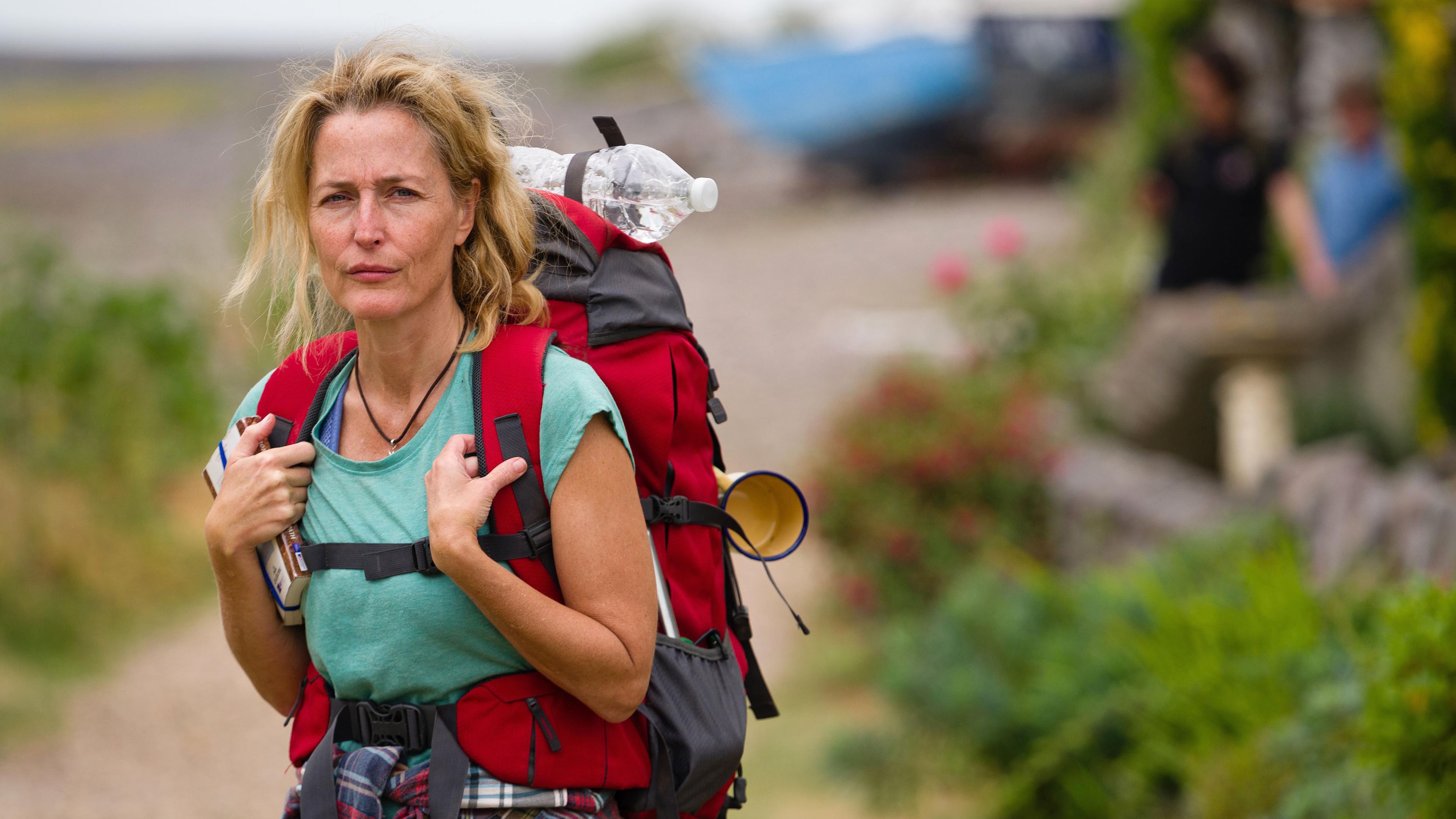 Eine blonde Frau trägt einen Trekkingrucksack.