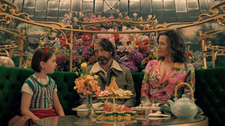 Ein Mädchen, ein Mann und eine Frau sitzen an einer im Art-Nouveau-Stil geschmückten Kaffee-Tafel.